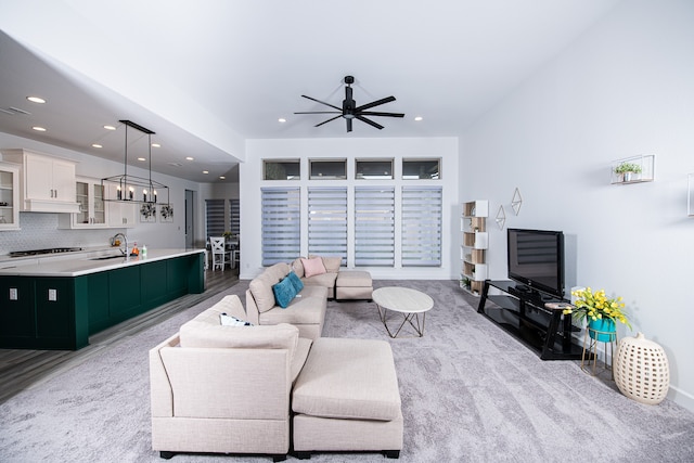 carpeted living room featuring ceiling fan and sink