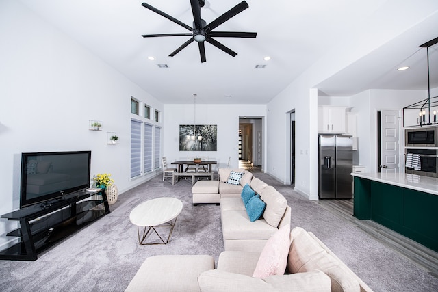 carpeted living room with ceiling fan with notable chandelier