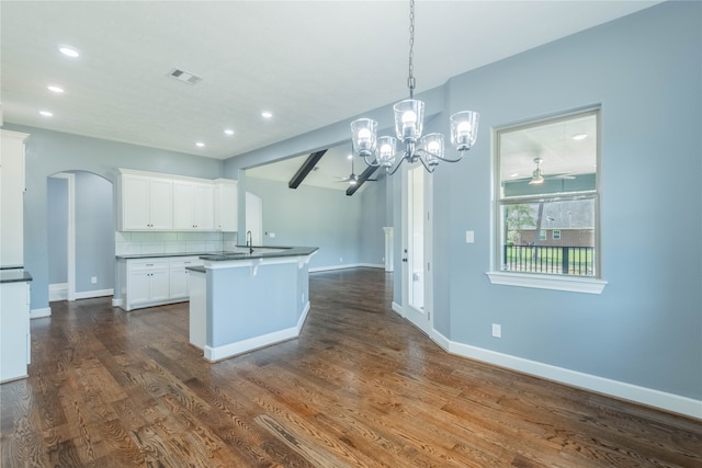 kitchen with pendant lighting, tasteful backsplash, dark wood-type flooring, white cabinetry, and ceiling fan with notable chandelier