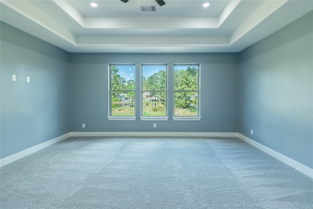 spare room featuring ceiling fan, a tray ceiling, and carpet