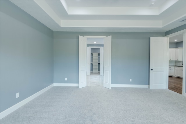 carpeted spare room featuring a raised ceiling