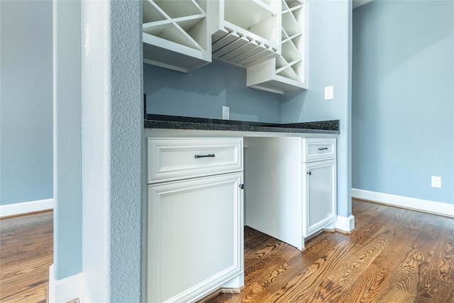 bar with hardwood / wood-style flooring and white cabinetry