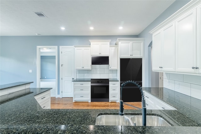 kitchen with decorative backsplash, white cabinets, hardwood / wood-style flooring, and sink