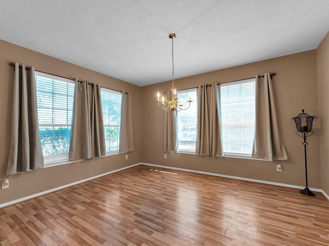 unfurnished room featuring light hardwood / wood-style floors and a chandelier