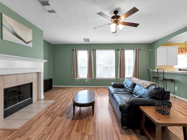 living room with ceiling fan, a fireplace, and light hardwood / wood-style flooring