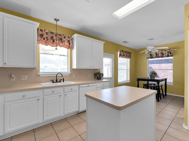 kitchen featuring a wealth of natural light, dishwasher, sink, and white cabinets