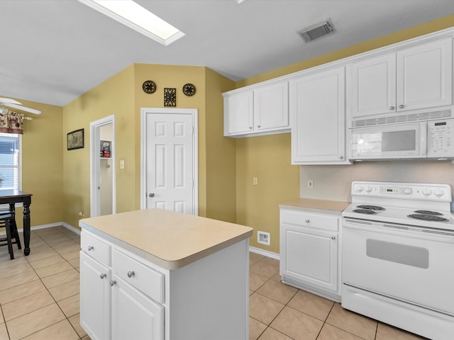 kitchen featuring white appliances, a center island, white cabinetry, and light tile patterned flooring