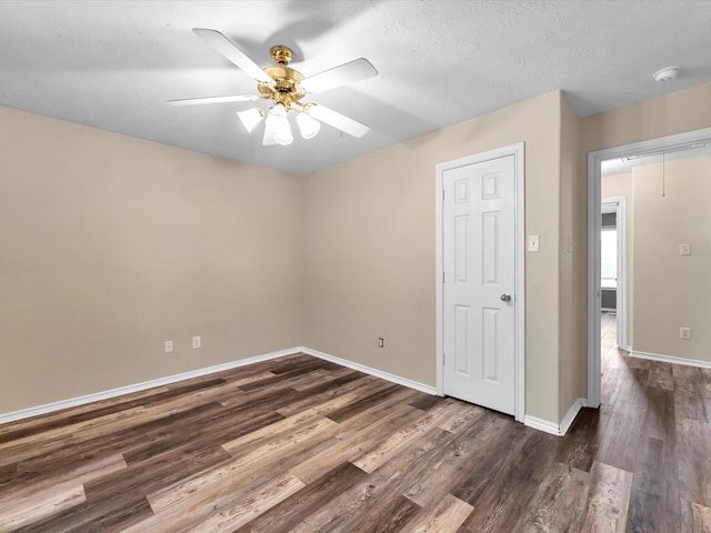 empty room with a textured ceiling, ceiling fan, and dark wood-type flooring