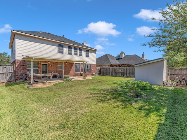 rear view of property featuring a storage unit, a yard, and a patio