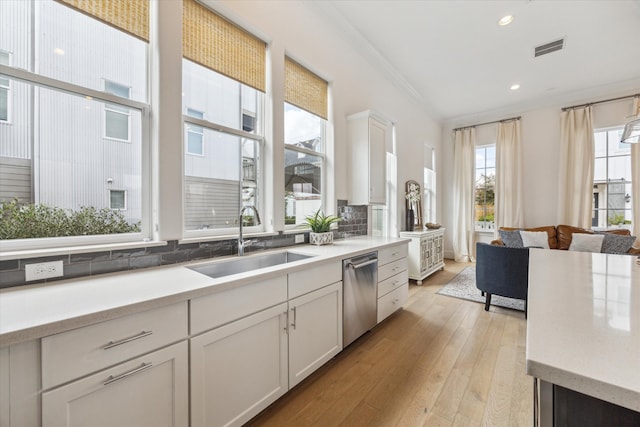 kitchen featuring dishwasher, tasteful backsplash, sink, white cabinetry, and crown molding