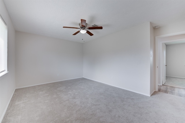 spare room featuring a textured ceiling, light carpet, and ceiling fan