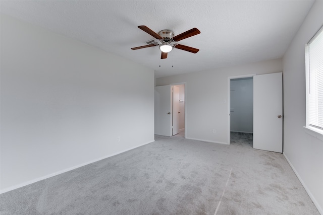 unfurnished bedroom featuring ceiling fan, multiple windows, a closet, and a spacious closet