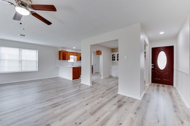 foyer entrance with light wood-type flooring, a textured ceiling, and ceiling fan