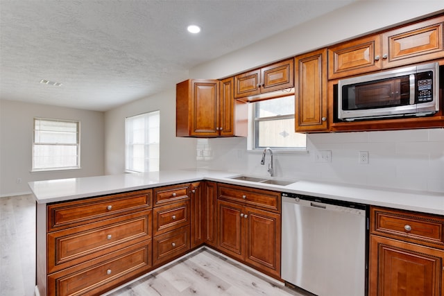 kitchen with kitchen peninsula, a healthy amount of sunlight, sink, and appliances with stainless steel finishes