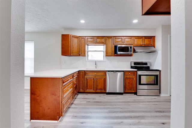 kitchen featuring a textured ceiling, appliances with stainless steel finishes, sink, and light hardwood / wood-style flooring