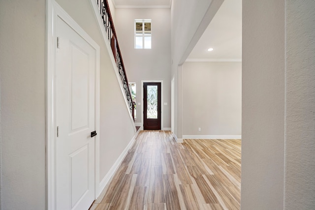 entrance foyer with light wood-type flooring, ornamental molding, and a wealth of natural light