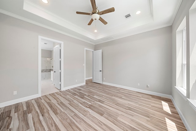 unfurnished bedroom with light hardwood / wood-style floors, connected bathroom, crown molding, a tray ceiling, and ceiling fan