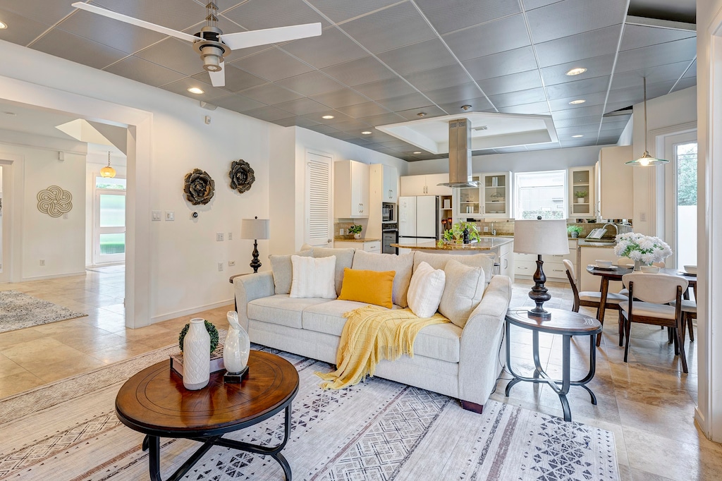 living room featuring ceiling fan, light tile patterned floors, and a tray ceiling