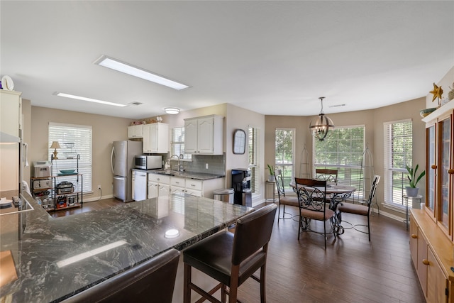 kitchen featuring tasteful backsplash, stainless steel appliances, decorative light fixtures, dark hardwood / wood-style floors, and sink