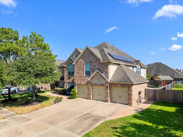 view of front of home featuring a garage, solar panels, and a front lawn