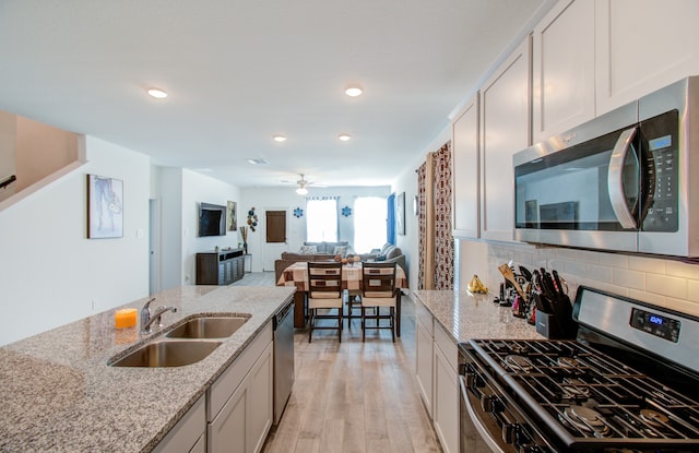 kitchen featuring light wood-type flooring, white cabinetry, light stone countertops, and stainless steel appliances