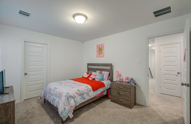 bedroom with a textured ceiling and light colored carpet