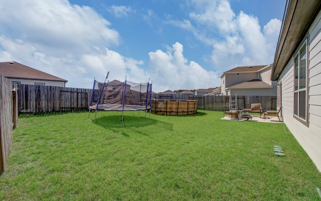 view of yard with a trampoline, a pool, and a patio area