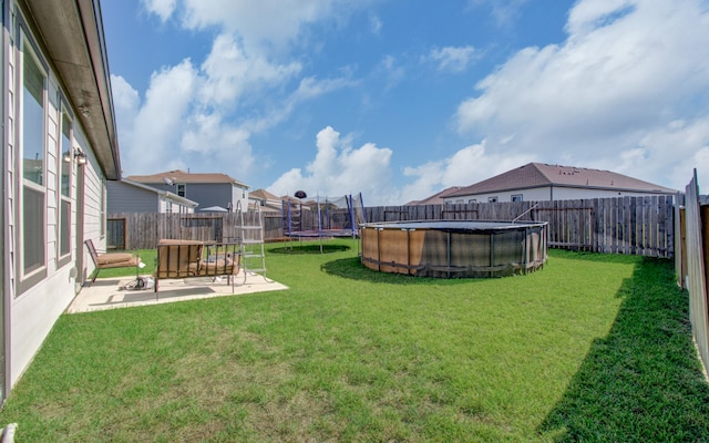 view of yard with a trampoline, a patio, and a fenced in pool