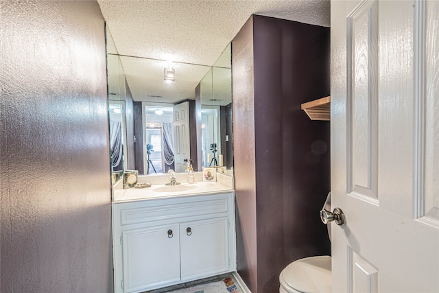 bathroom featuring a textured ceiling, vanity, and toilet