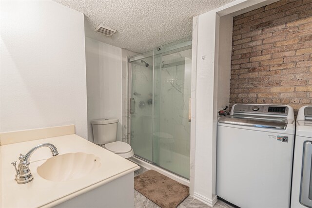 bathroom featuring washing machine and dryer, vanity, toilet, and a shower with shower door