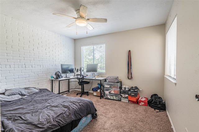 carpeted bedroom featuring a textured ceiling, ceiling fan, and brick wall