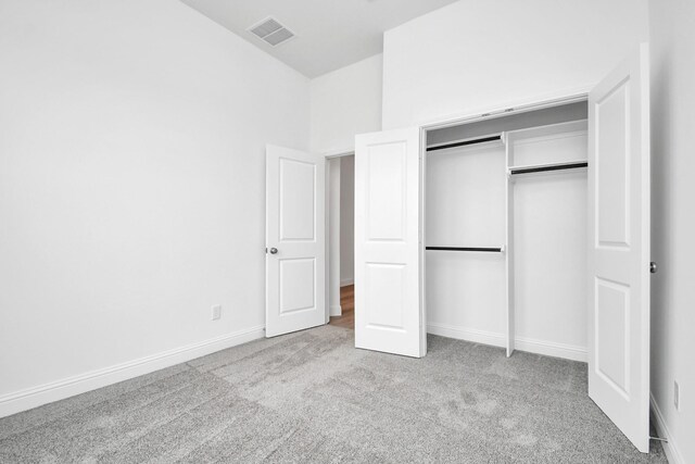 unfurnished bedroom with light carpet and a closet