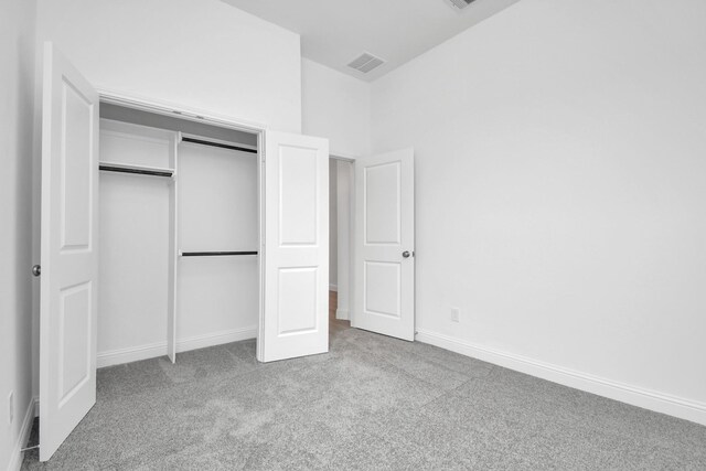 unfurnished bedroom featuring light carpet and a closet