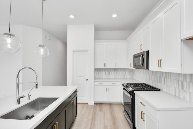 kitchen featuring appliances with stainless steel finishes, hanging light fixtures, and white cabinetry