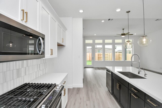 kitchen with sink, white cabinetry, hanging light fixtures, stainless steel appliances, and ceiling fan