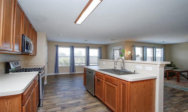 kitchen featuring appliances with stainless steel finishes, a center island with sink, dark hardwood / wood-style flooring, and a healthy amount of sunlight