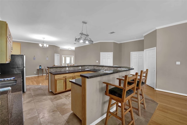 kitchen featuring a kitchen island, light hardwood / wood-style flooring, a kitchen bar, a notable chandelier, and pendant lighting