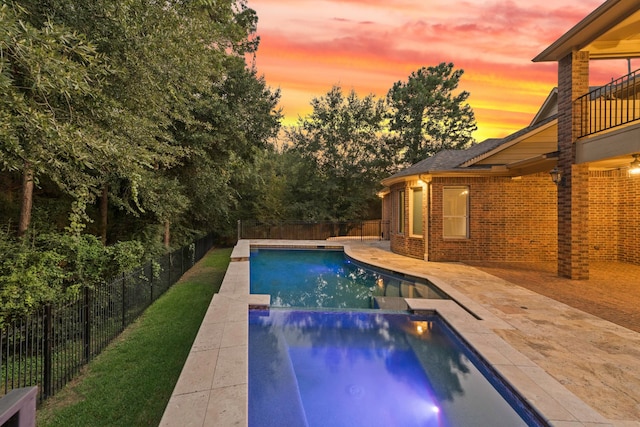 pool at dusk featuring a patio