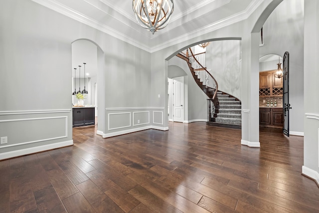 foyer with ornamental molding, an inviting chandelier, and dark wood-type flooring