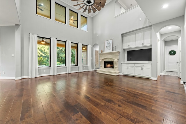 unfurnished living room with high vaulted ceiling, ceiling fan, and dark hardwood / wood-style floors