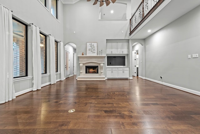 unfurnished living room with a high ceiling, dark hardwood / wood-style floors, and ceiling fan