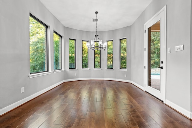 unfurnished dining area with an inviting chandelier, plenty of natural light, and dark hardwood / wood-style flooring