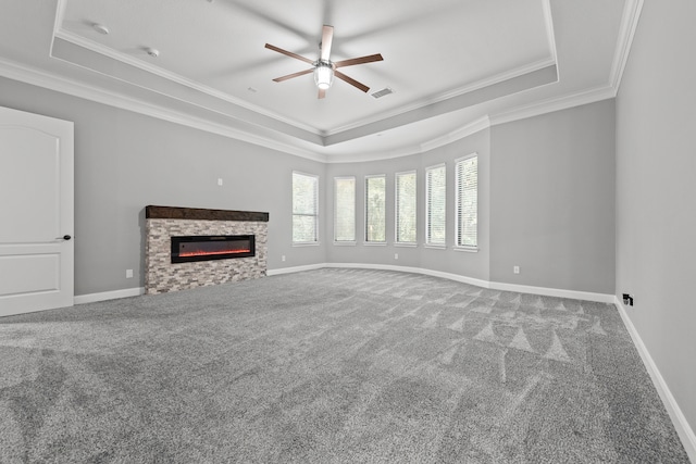 unfurnished living room featuring ceiling fan, a tray ceiling, crown molding, and carpet flooring