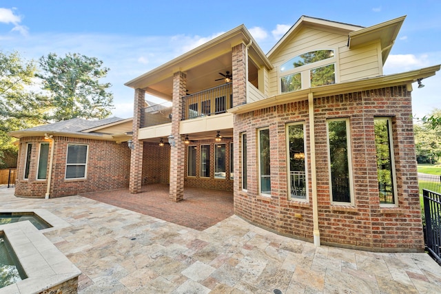 rear view of property with a balcony, ceiling fan, and a patio area