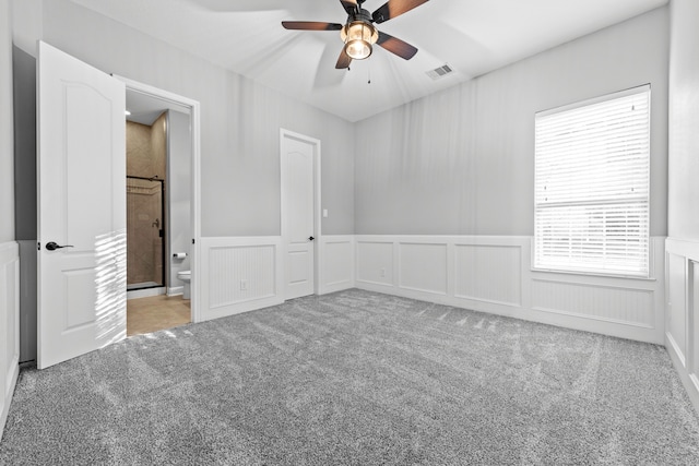 interior space featuring connected bathroom, light carpet, ceiling fan, and a closet