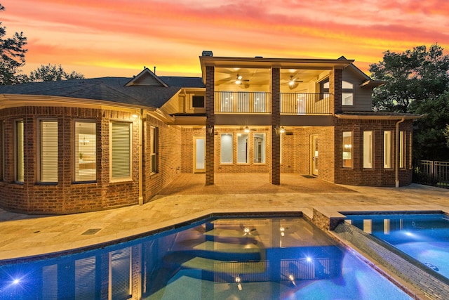 pool at dusk with a hot tub and a patio