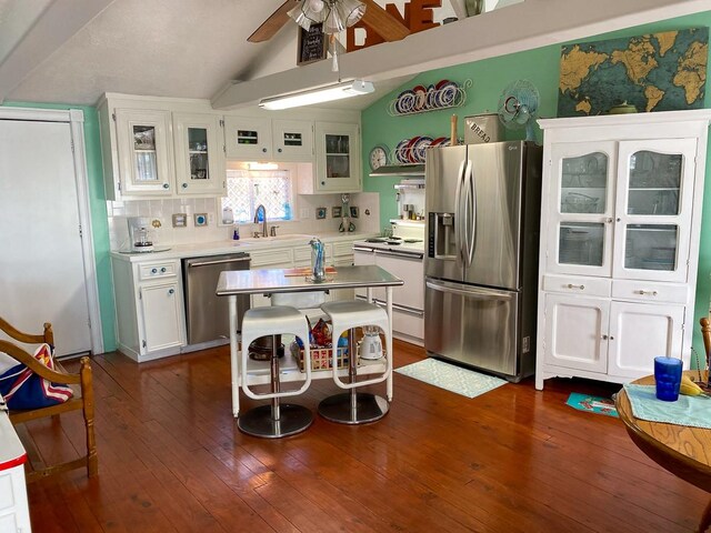 kitchen with ceiling fan, white cabinetry, stainless steel appliances, vaulted ceiling, and dark hardwood / wood-style flooring