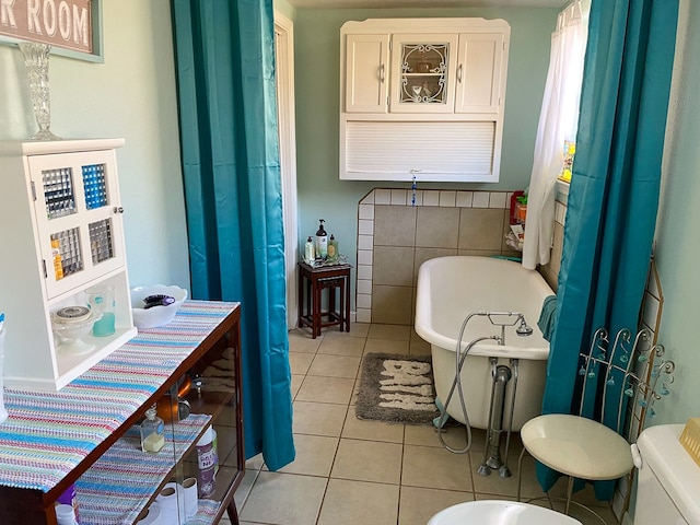 bathroom with a tub to relax in, toilet, and tile patterned floors