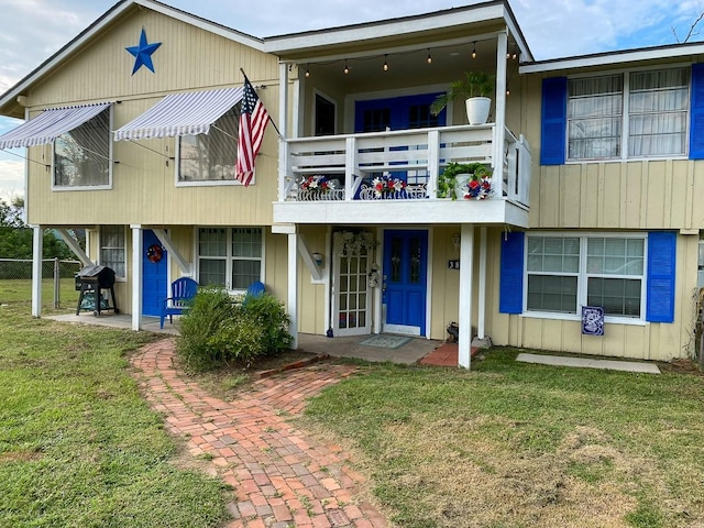 view of front of home with a balcony and a front yard