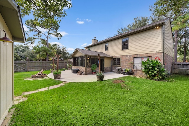 rear view of property with a yard, a patio, and a sunroom